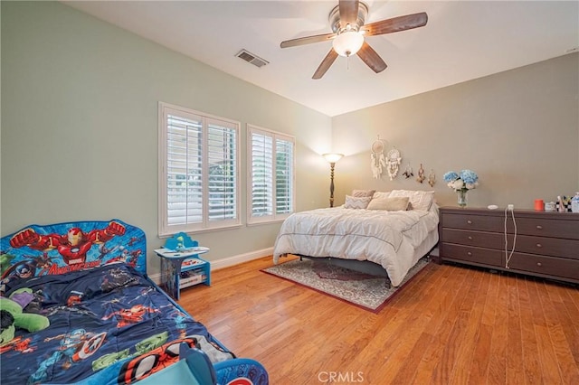bedroom featuring baseboards, visible vents, wood finished floors, and a ceiling fan