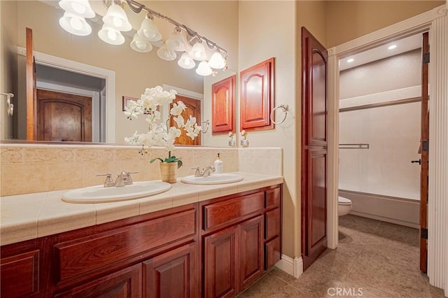 bathroom featuring an inviting chandelier, tile patterned floors, double vanity, toilet, and a sink
