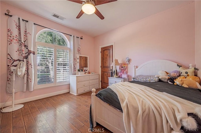 bedroom featuring visible vents, ceiling fan, hardwood / wood-style floors, and baseboards