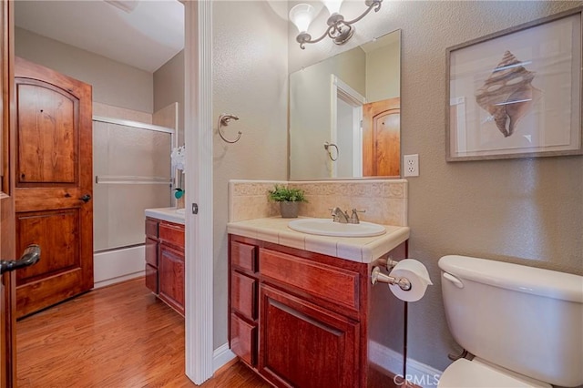 bathroom with tasteful backsplash, wood finished floors, toilet, a textured wall, and vanity