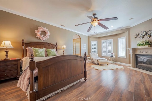 bedroom featuring visible vents, a fireplace with flush hearth, wood finished floors, and baseboards