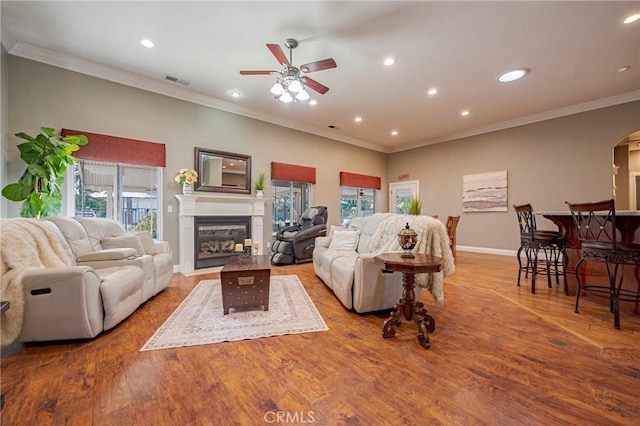 living area featuring recessed lighting, arched walkways, ceiling fan, a glass covered fireplace, and visible vents