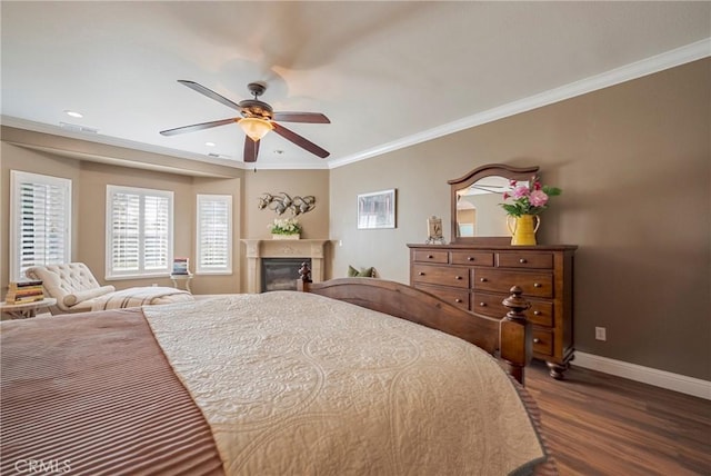 bedroom with crown molding, visible vents, dark wood-style floors, baseboards, and a glass covered fireplace