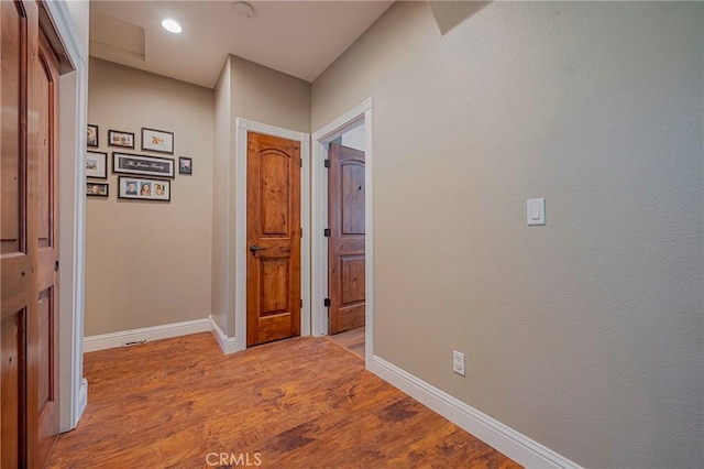 hallway featuring recessed lighting, baseboards, and light wood-style floors