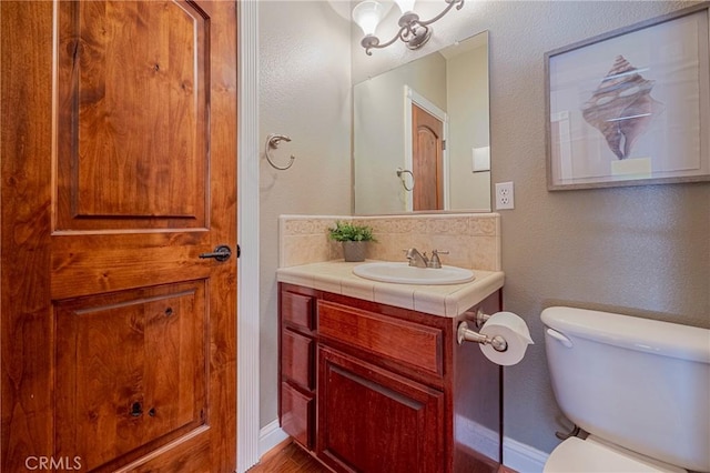 bathroom with toilet, a textured wall, and vanity