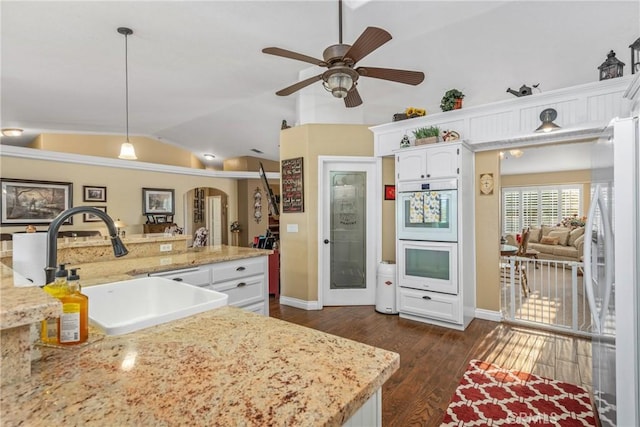 kitchen with white cabinets, white appliances, lofted ceiling, a sink, and dark wood-style floors
