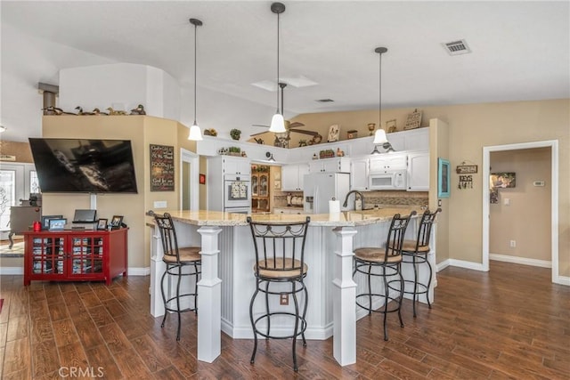 kitchen with vaulted ceiling, white appliances, visible vents, white cabinets, and dark wood-style flooring
