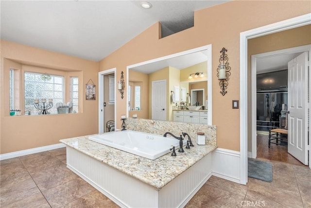 bathroom with a garden tub, vaulted ceiling, vanity, and plenty of natural light