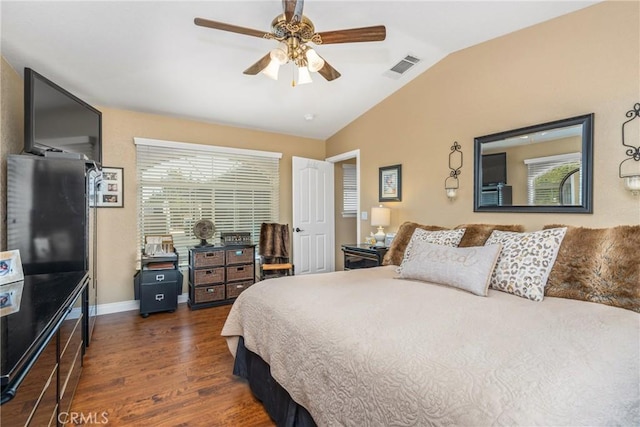 bedroom featuring dark wood-style floors, lofted ceiling, baseboards, visible vents, and ceiling fan