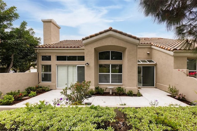 exterior space featuring stucco siding, fence, a chimney, and a tiled roof