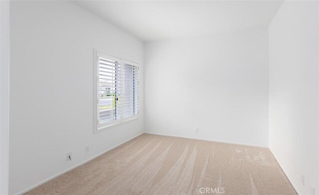 spare room featuring carpet floors and baseboards