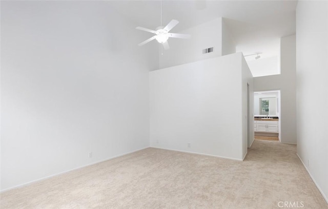 spare room with light colored carpet, visible vents, a ceiling fan, and a high ceiling