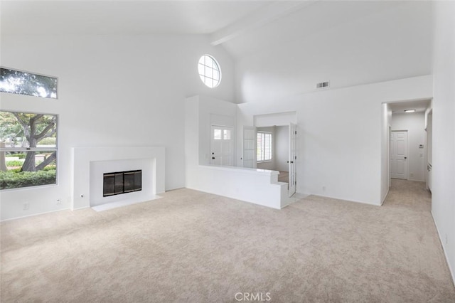 unfurnished living room with carpet flooring, a fireplace with flush hearth, beam ceiling, high vaulted ceiling, and visible vents