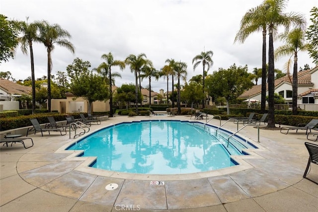 community pool with a patio and fence