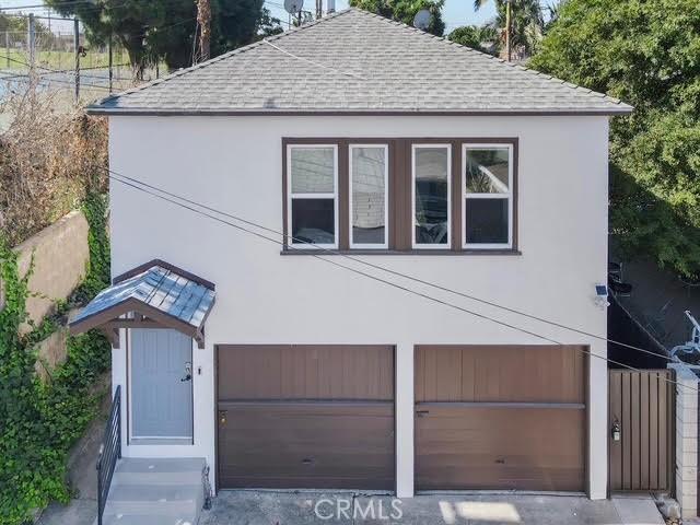 610 E Fairview, Inglewood, CA 90302 - view of front of home featuring a shingled roof, fence, stucco siding, and an attached garage