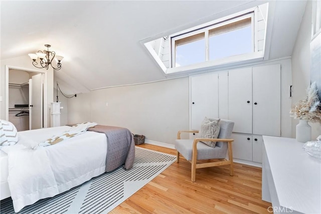 bedroom with light wood finished floors, vaulted ceiling, a closet, and a notable chandelier