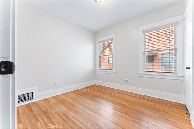 spare room featuring baseboards, visible vents, and light wood-type flooring