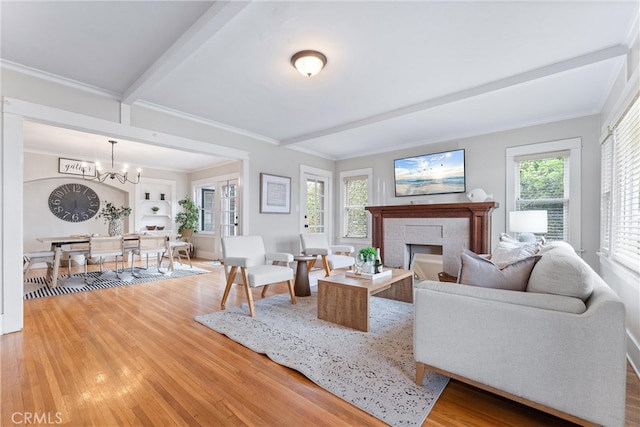 living room with a chandelier, crown molding, a brick fireplace, wood finished floors, and beam ceiling