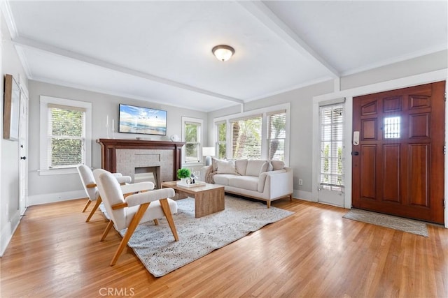living room featuring baseboards, beam ceiling, and light wood finished floors