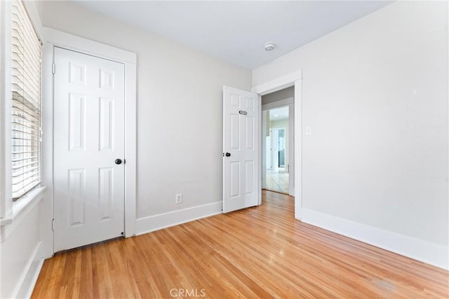 unfurnished bedroom with baseboards and light wood-style flooring