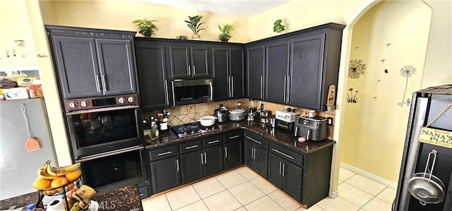 7445 Cedar St, Phelan, CA 92371 - kitchen featuring dark cabinetry, appliances with stainless steel finishes, backsplash, and light tile patterned floors