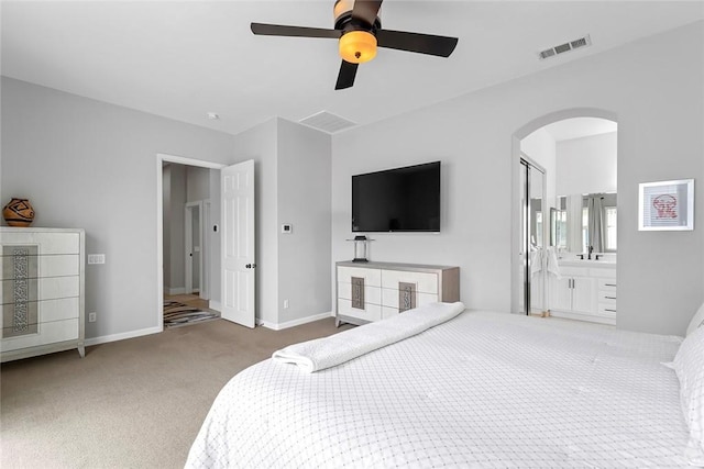 bedroom featuring baseboards, connected bathroom, carpet floors, visible vents, and arched walkways
