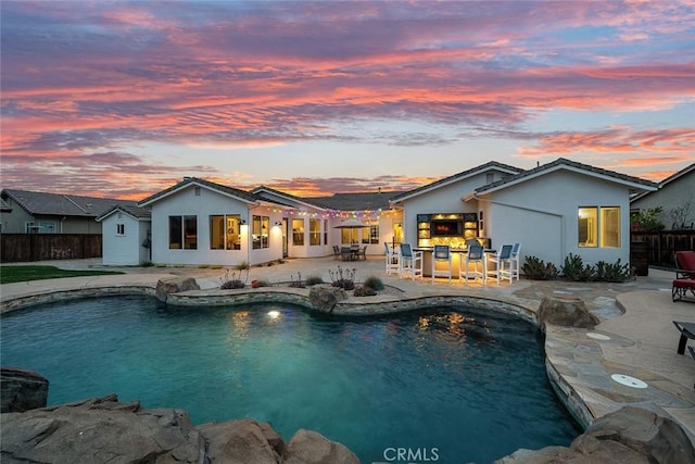 view of swimming pool with a patio, outdoor dry bar, a fenced in pool, and fence