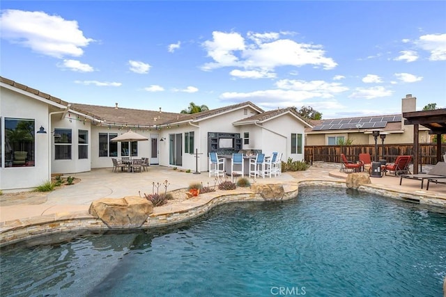 view of pool with outdoor dining space, a patio, fence, and an outdoor fire pit
