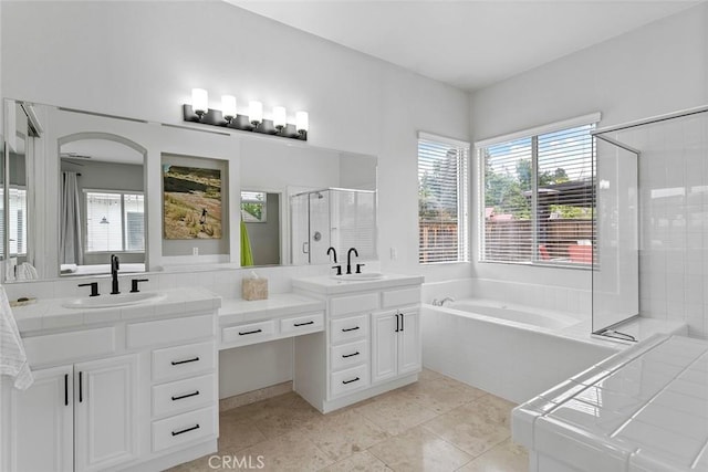 full bathroom featuring a bath, a stall shower, double vanity, and a sink