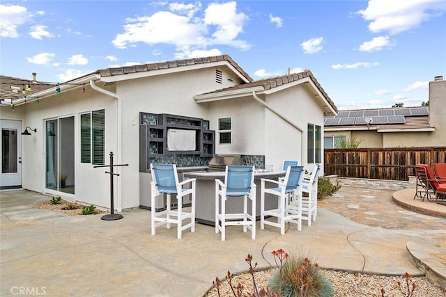 view of patio featuring outdoor dry bar, fence, and exterior kitchen