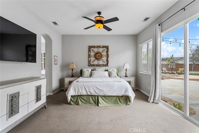carpeted bedroom featuring arched walkways, visible vents, access to exterior, and baseboards