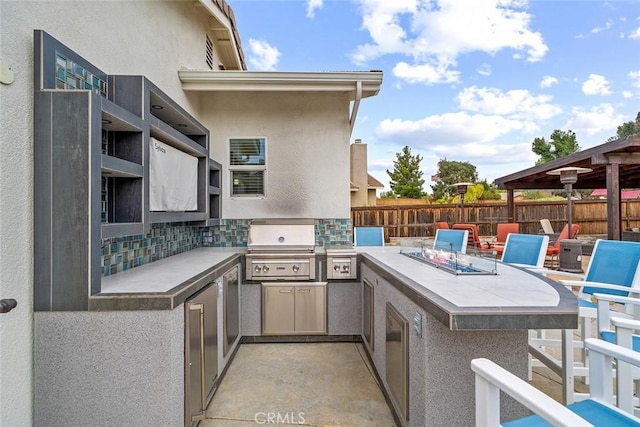 view of patio with fence, exterior kitchen, and area for grilling