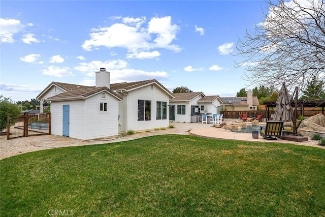 back of house featuring a tiled roof, a yard, a patio area, fence, and a chimney