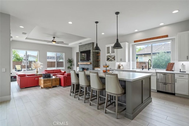 kitchen featuring white cabinets, light countertops, decorative backsplash, and a raised ceiling
