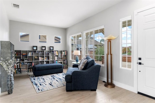 living room featuring visible vents, baseboards, and wood finished floors