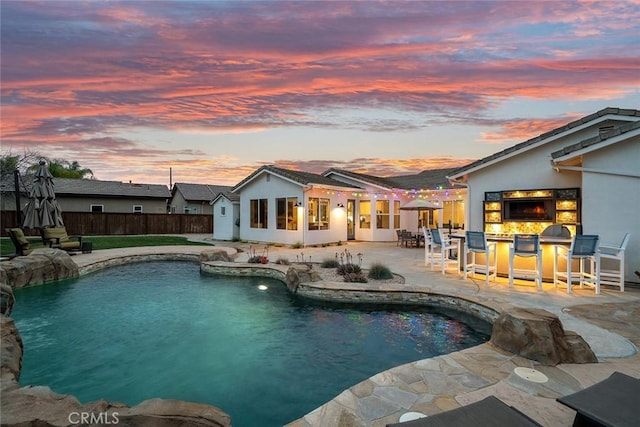 view of swimming pool with outdoor dry bar, a patio area, a fenced in pool, and fence