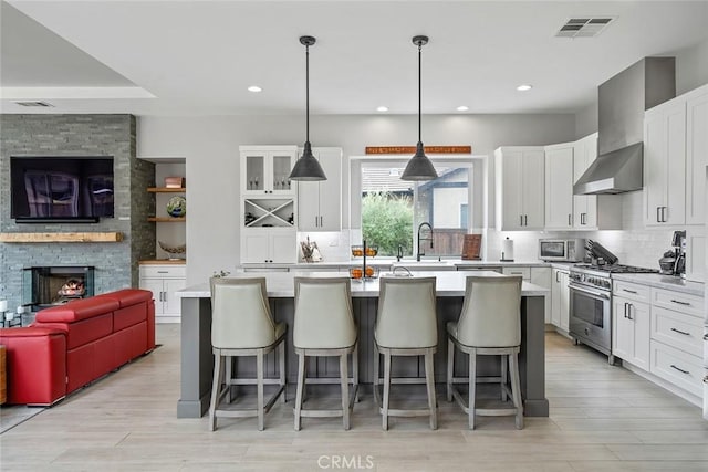kitchen featuring visible vents, open floor plan, wall chimney range hood, and stainless steel appliances