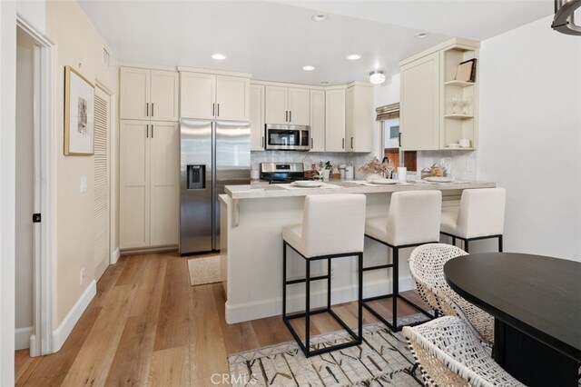 1517 Felspar St, San Diego, CA 92109 - kitchen featuring appliances with stainless steel finishes, a peninsula, a breakfast bar, light wood finished floors, and open shelves