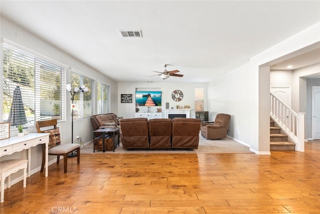 33734 Wild Horse Way, Yucaipa, CA 92399 - living room featuring light wood finished floors, a ceiling fan, stairs, baseboards, and a fireplace