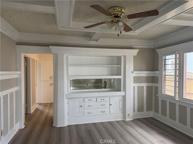 unfurnished living room with a ceiling fan, a decorative wall, a wainscoted wall, and dark wood finished floors