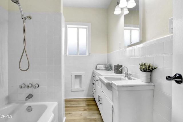 full bath with tile walls, shower / bathtub combination, vanity, and a healthy amount of sunlight