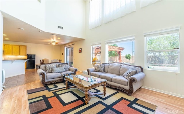living room with baseboards, visible vents, light wood-style flooring, and a ceiling fan