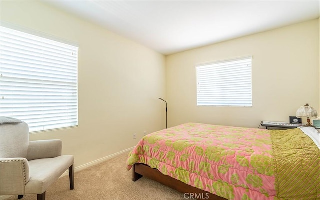 carpeted bedroom featuring baseboards and multiple windows