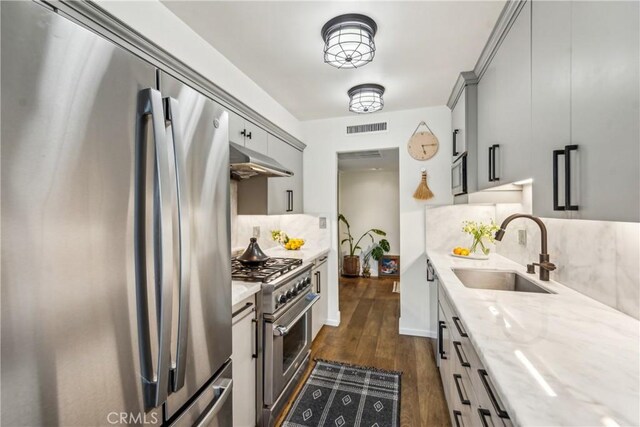 800 W 1st St Unit 1803, Los Angeles, CA 90012 - kitchen with appliances with stainless steel finishes, a sink, under cabinet range hood, backsplash, and dark wood finished floors