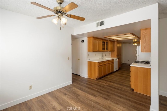 kitchen with a textured ceiling, light countertops, visible vents, white appliances, and dark wood-type flooring
