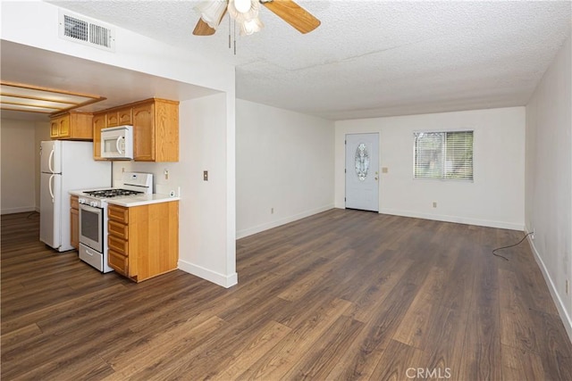 kitchen with light countertops, white appliances, dark wood finished floors, visible vents, and a ceiling fan