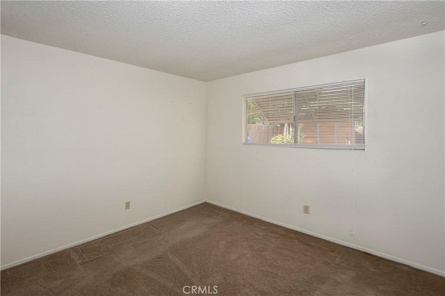 spare room featuring baseboards, carpet floors, and a textured ceiling