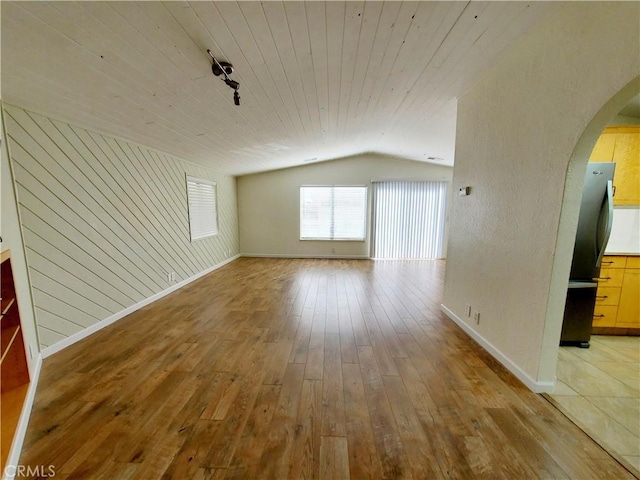327 Mccarthy Ave, Oceano, CA 93445 - unfurnished room with arched walkways, lofted ceiling, baseboards, light wood-type flooring, and wood walls