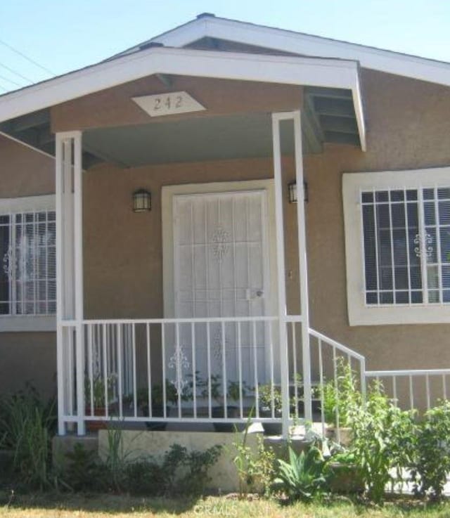 242 E 92nd St, Los Angeles, CA 90003 - doorway to property with stucco siding and a porch