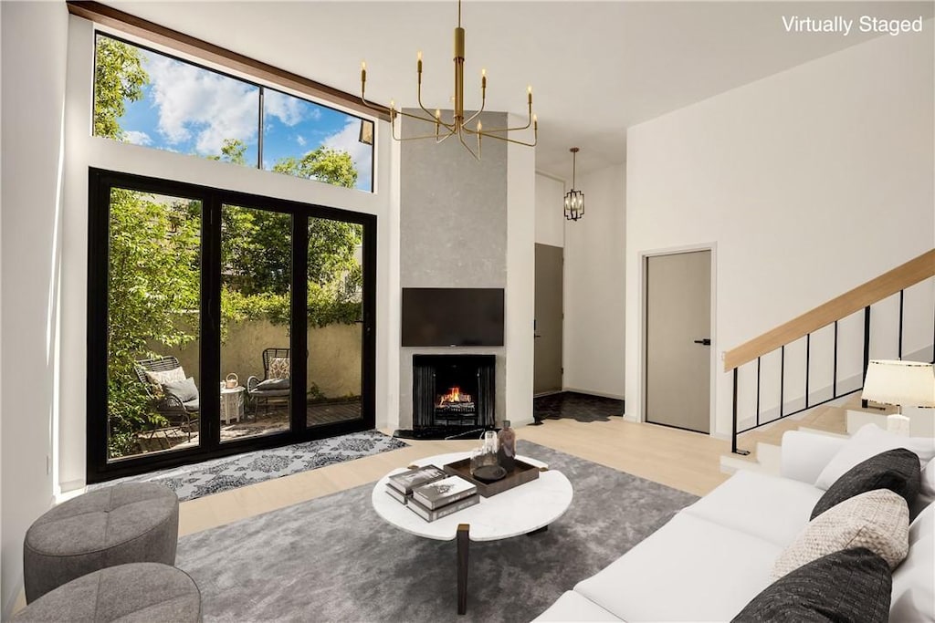 living area featuring an inviting chandelier, a towering ceiling, stairs, and wood finished floors